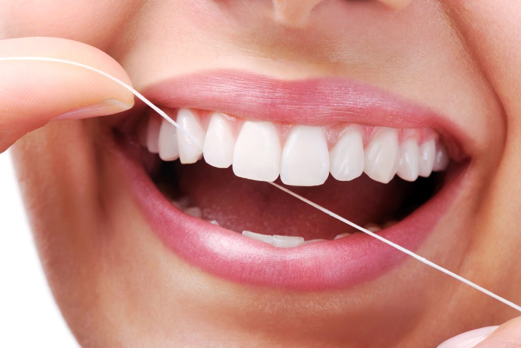 Prophylaxe - Frau die Zahnseide benützt